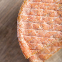 A close up photo of the pink and white wrinkly rind of Gubbeen cheese.