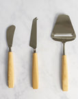 A set of three Bjorklund knives for cheese arranged vertically on a marble work top.
