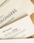 A £20 London Cheesemongers gift voucher and envelope on a wooden board.