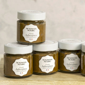 Jars of maison marc tapenade of aubergine on a wooden board.