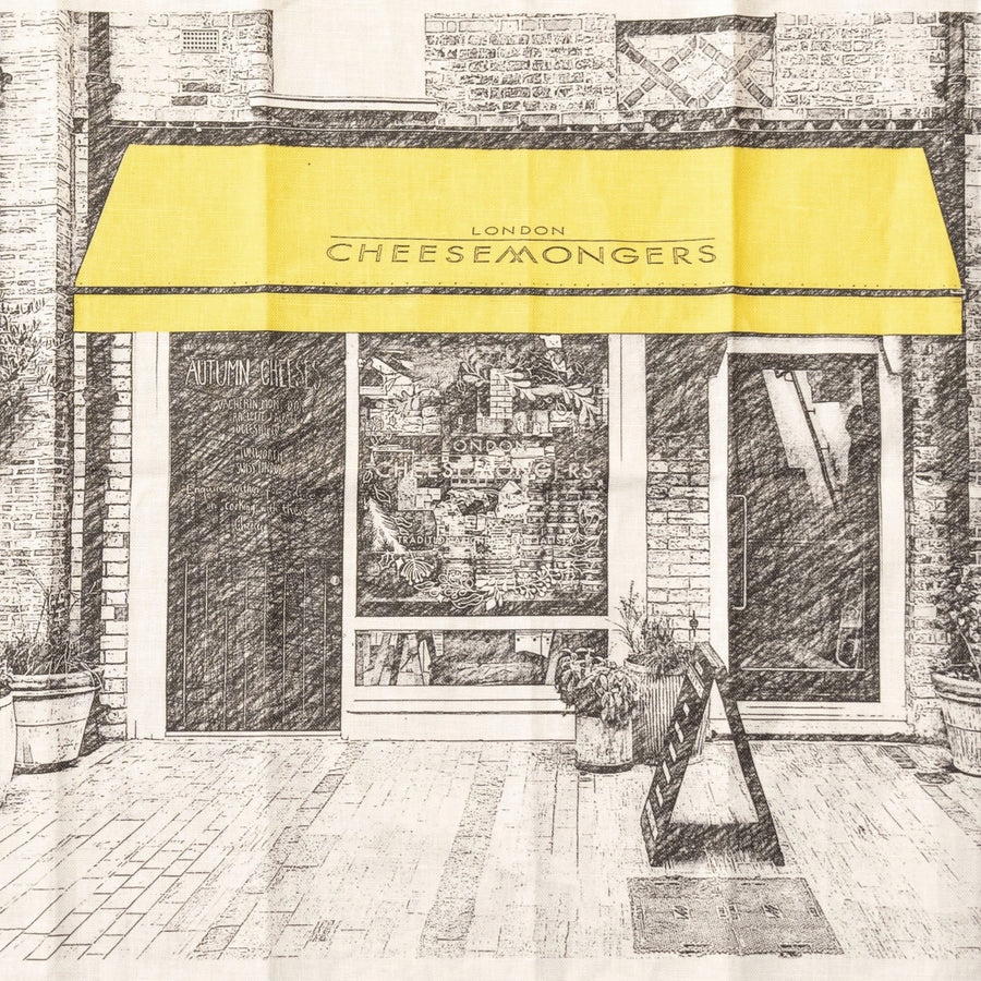 A tea towel depicting the front of a shop with a yellow awning.