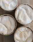 Four round boxes of Vacherin cheese on a wooden surface