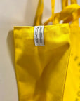 A close up of the branded label on a yellow canvas tote bag.