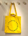 The yellow canvas London Cheesemongers tote bag hanging on the wall.