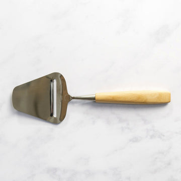 A wooden handled cheese slicer on a marble work top.