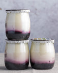 Three pots of blueberry compote yoghurt in glass jars.