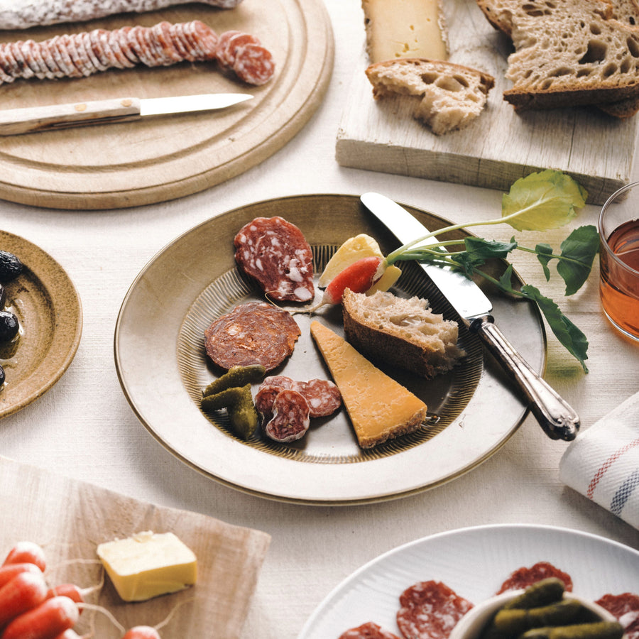 A plate containing a selection of cheese, charcuterie and bread.