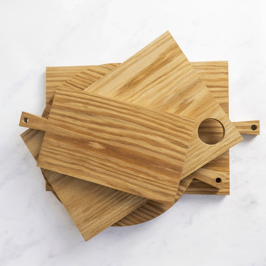 A stack of wooden chopping boards of various sizes on a marble worktop.