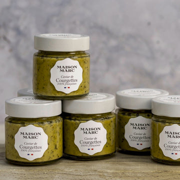 Jars of maison marc tapenade of courgette on a wooden board.