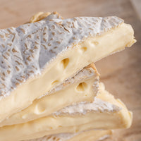 Close up of the oozing cut side of pieces of Brie soft cheese.
