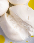 A cut Burrata cheese on a plate drizzled with some olive oil.