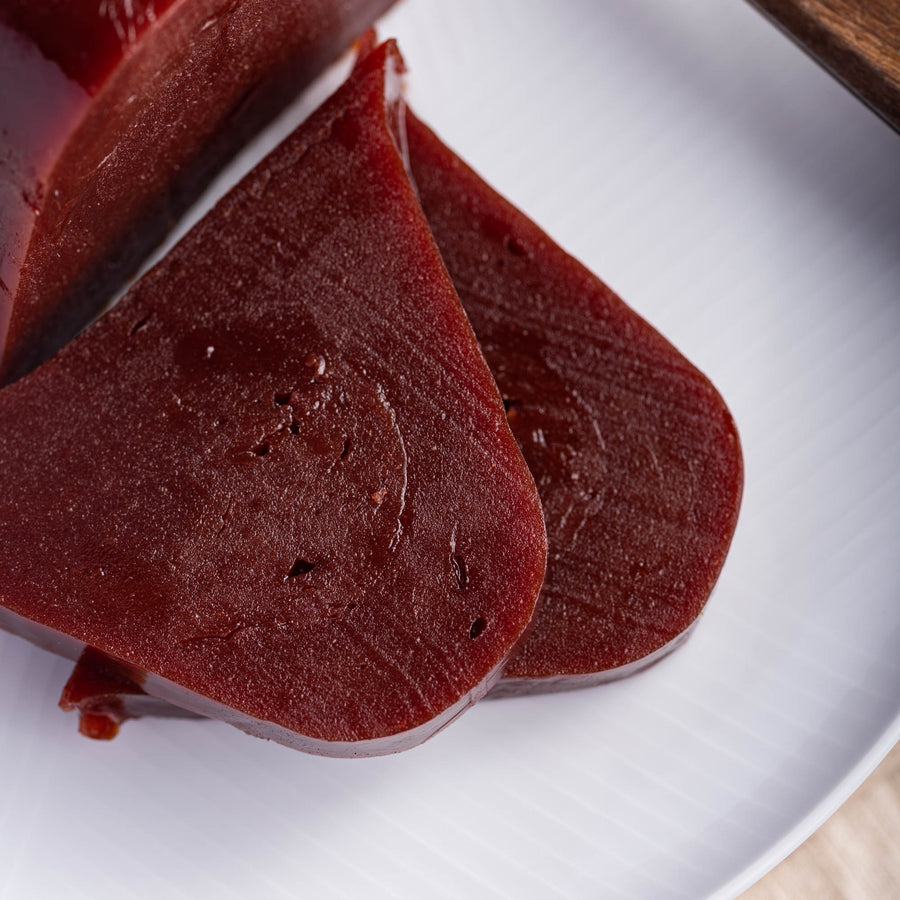 Slices of crimson quince paste on a white plate.