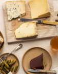 A selection of cheese, accompaniments and wine on plates and a wooden board.