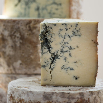 A cut piece of Stilton blue cheese on a whole Stilton cheese.