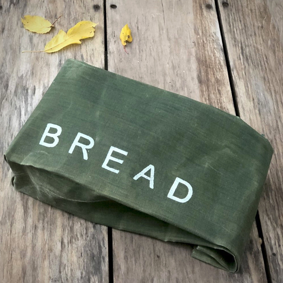 A green waxed bread bag on a wooden table.