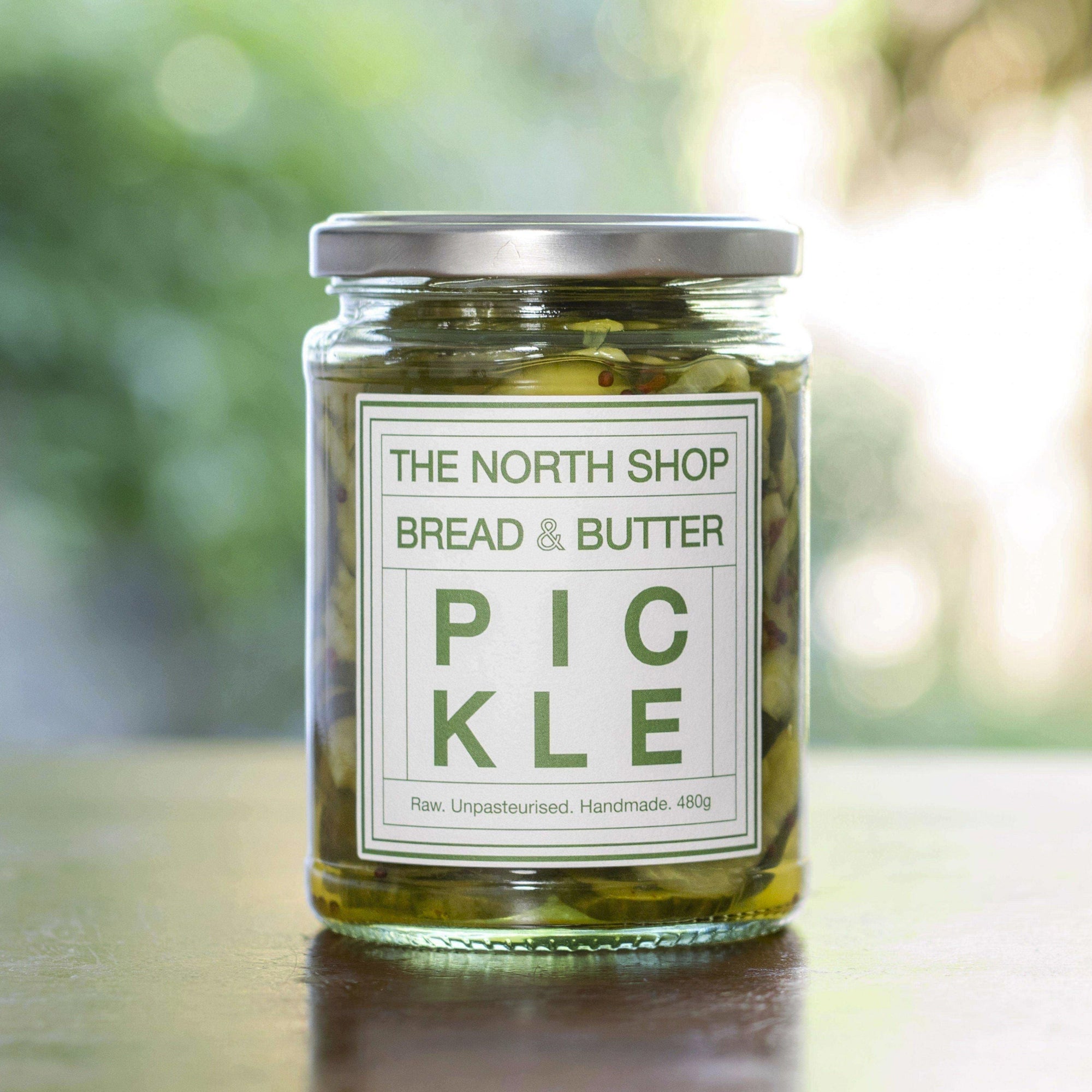 Jar of pickles with a label on a blurred natural background.