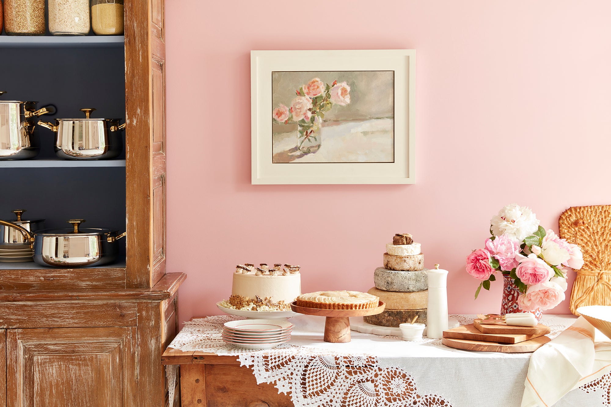 A table set with cakes and a selection of whole cheeses on wooden boards.
