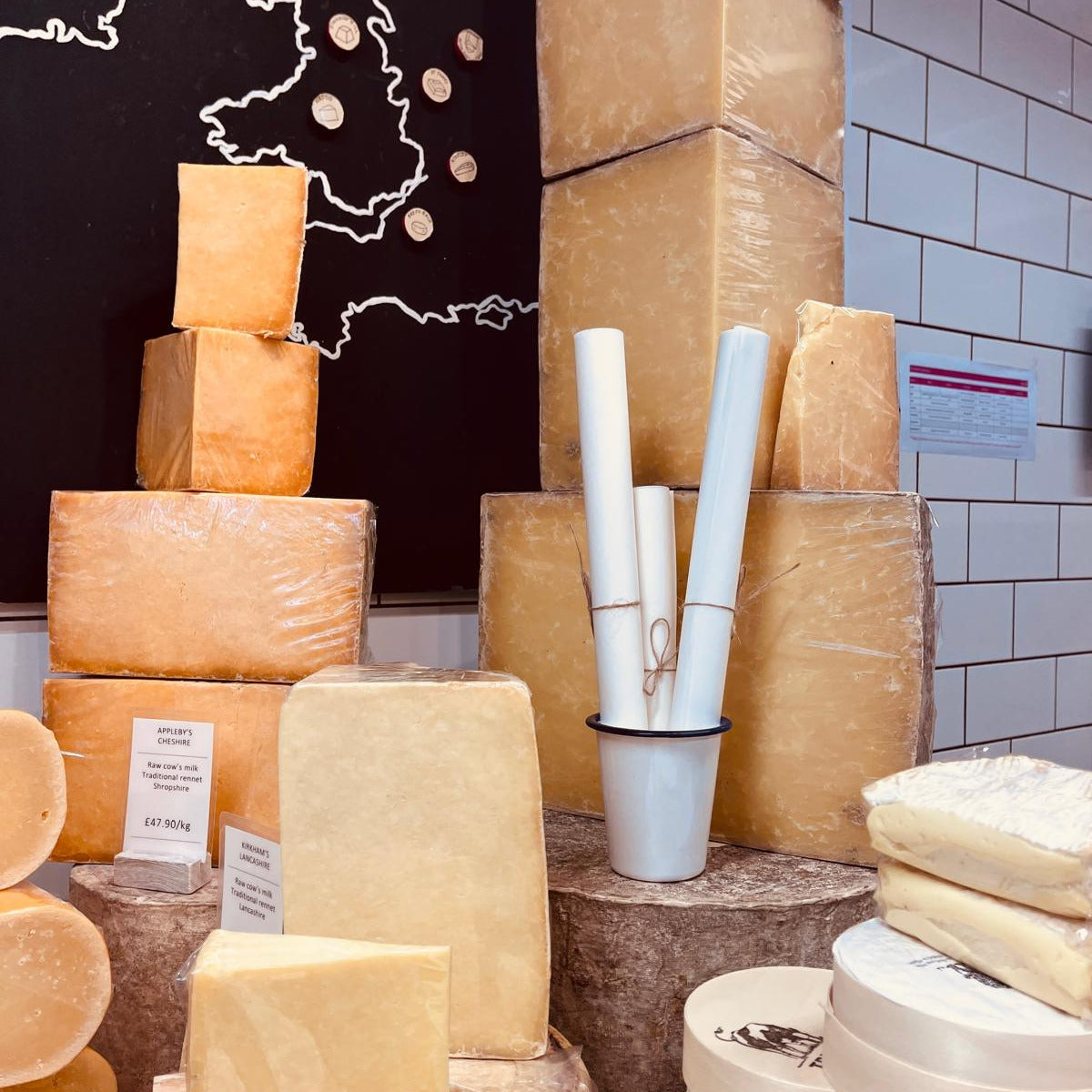 Display of various types of cheese with some wrapped in paper.