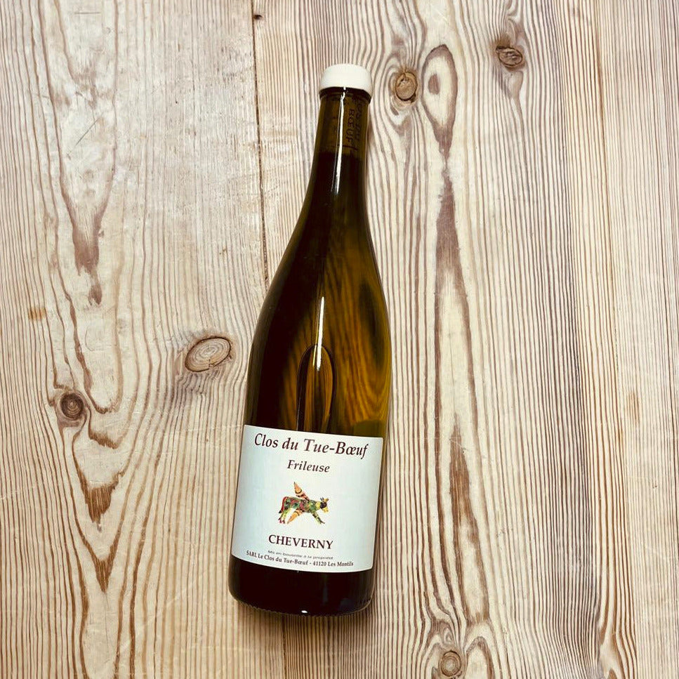 A bottle of white wine on a wooden table.