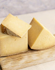 Cut pieces of Corra Linn cheese on a wooden board.