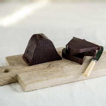 Slices of damson paste with a knife on a wooden board.