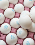 A tray of white hen's eggs in a pink cardboard tray.