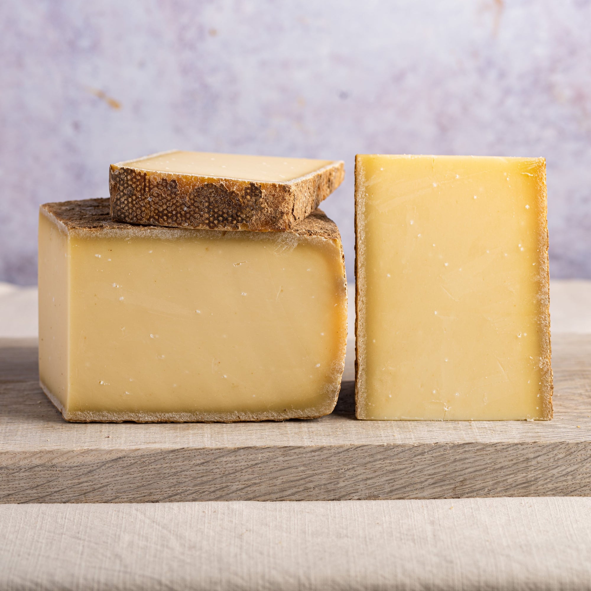 Pieces of cut cheese on a wooden board.
