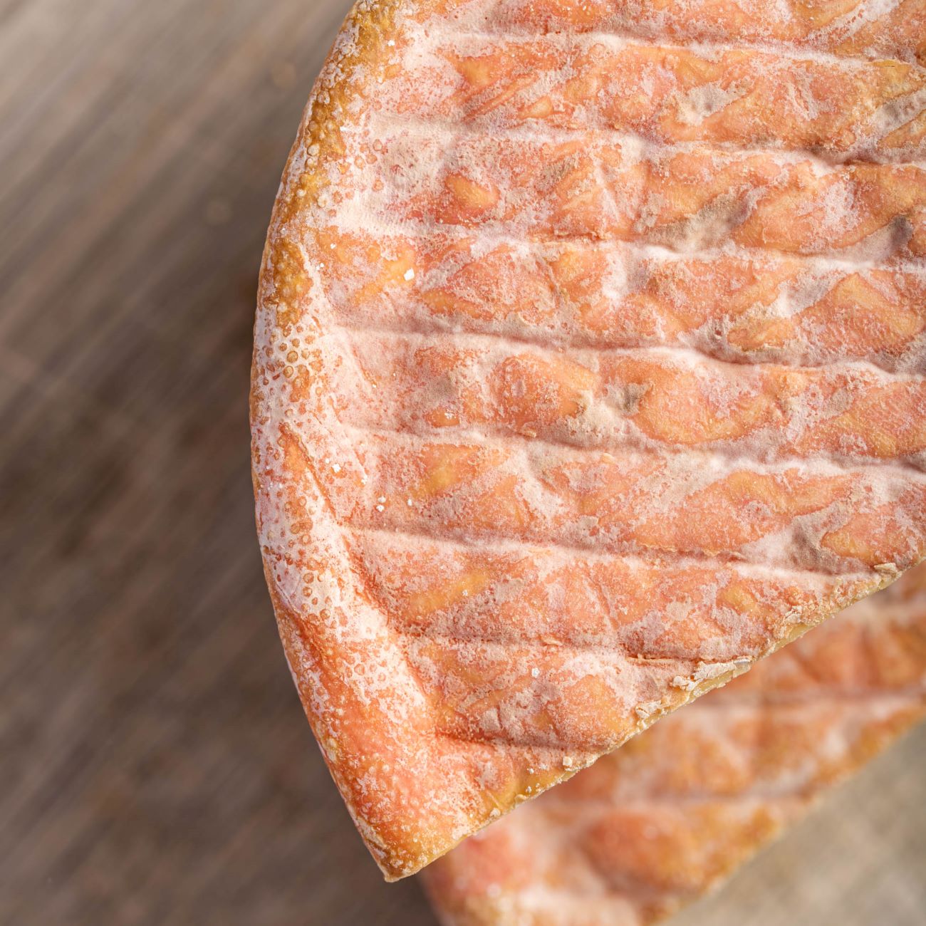 A close up photo of the pink and white wrinkly rind of Gubbeen cheese.