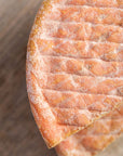 A close up photo of the pink and white wrinkly rind of Gubbeen cheese.
