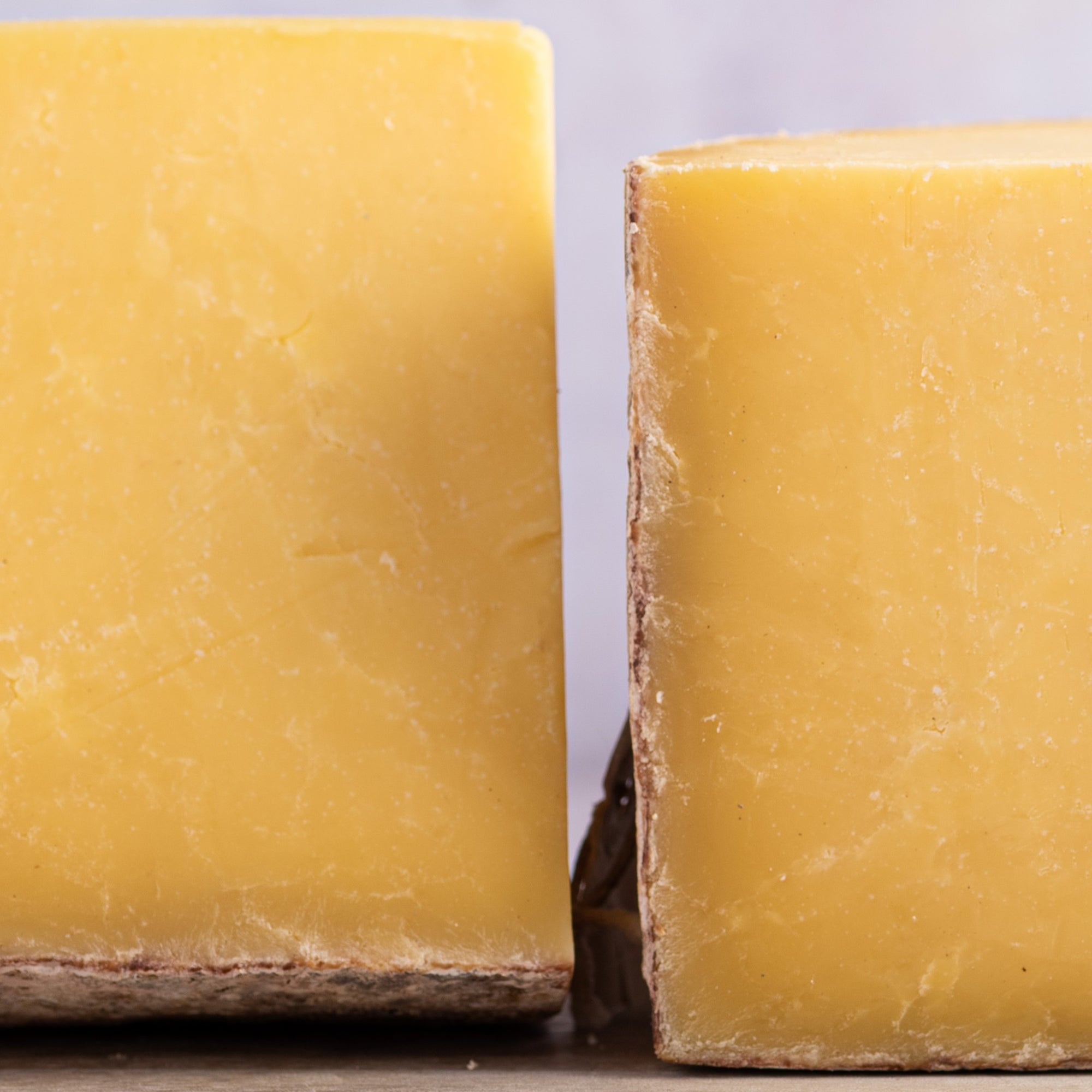 Close up of cut sides of yellow cheese on a board.