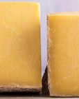 Close up of cut sides of yellow cheese on a board.