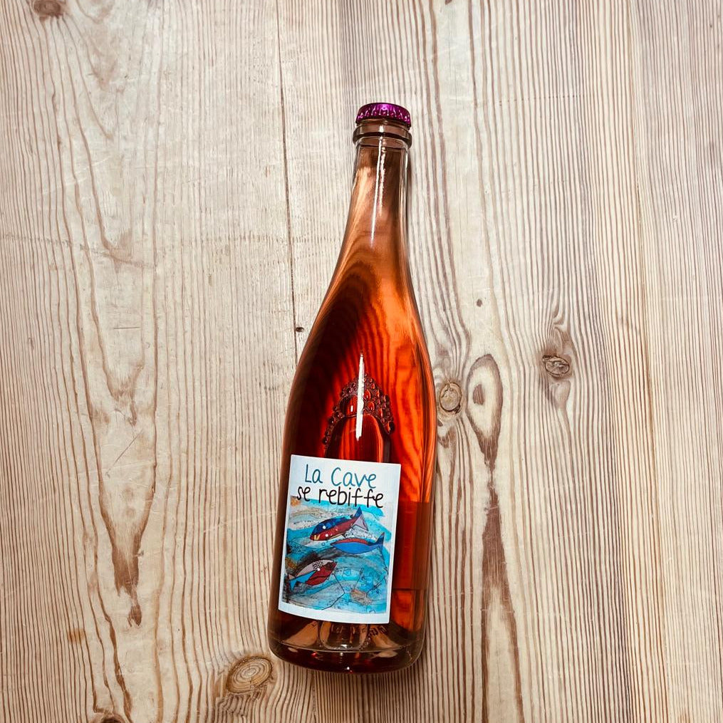 Bottle of sparkling rosé wine on a wooden table.