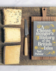Three cuts of cheese on a wooden board, with a cheese knife and a paperback copy of Ned Palmer's 'A Cheesemonger's History of the British Isles'.