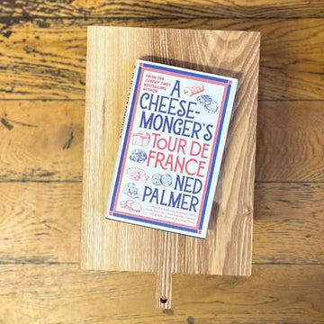 A hardback copy of Ned Palmer's 'Tour de France' book on  a wooden chopping board.