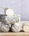 A stack of Oiselliere French goat's cheese on a wooden board.