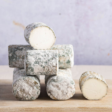 A stack of Oiselliere French goat's cheese on a wooden board.