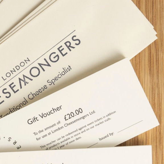 A £20 London Cheesemongers gift voucher and envelope on a wooden board.