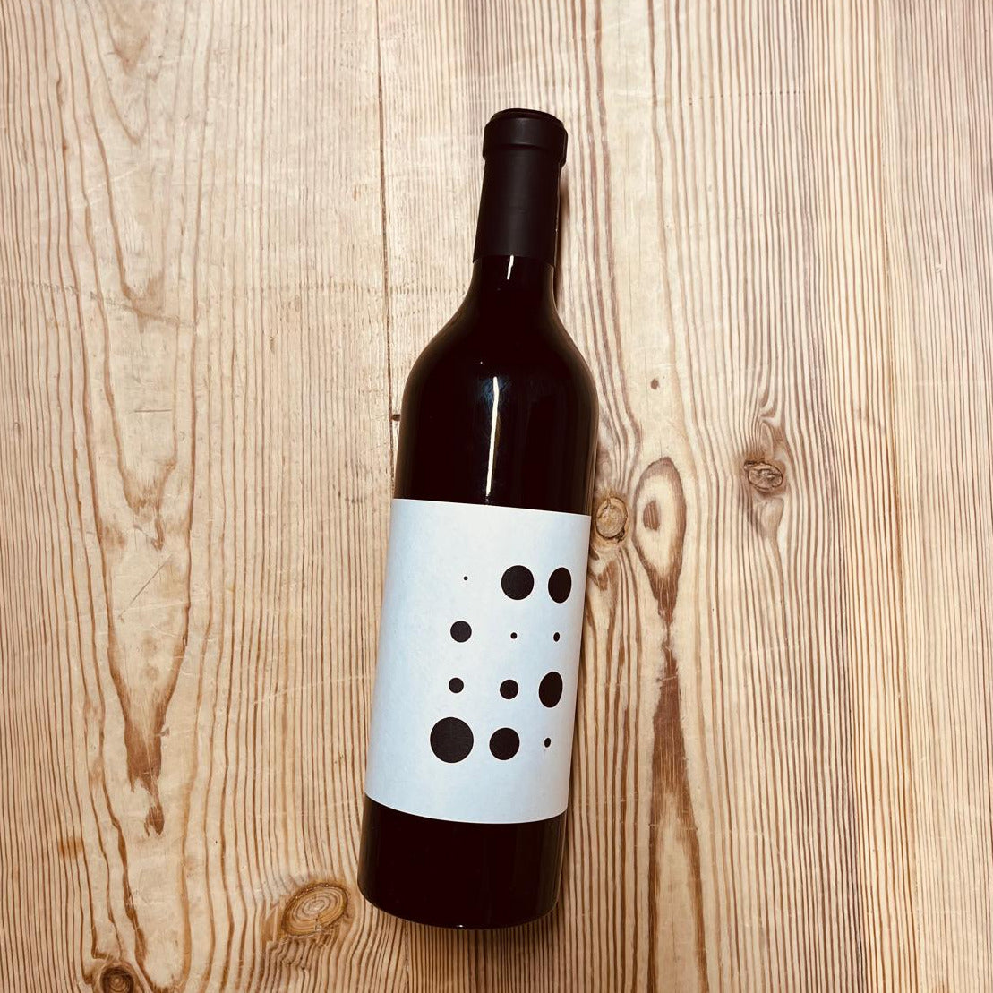 A bottle of wine with a white label on a wooden table.