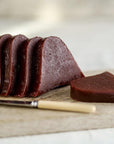 Slices of quince paste with a knife on a wooden board.