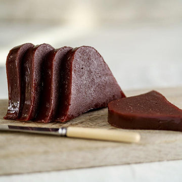 Slices of quince paste with a knife on a wooden board.