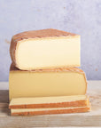 Stack of cheese wedges on a wooden board with a light purple background