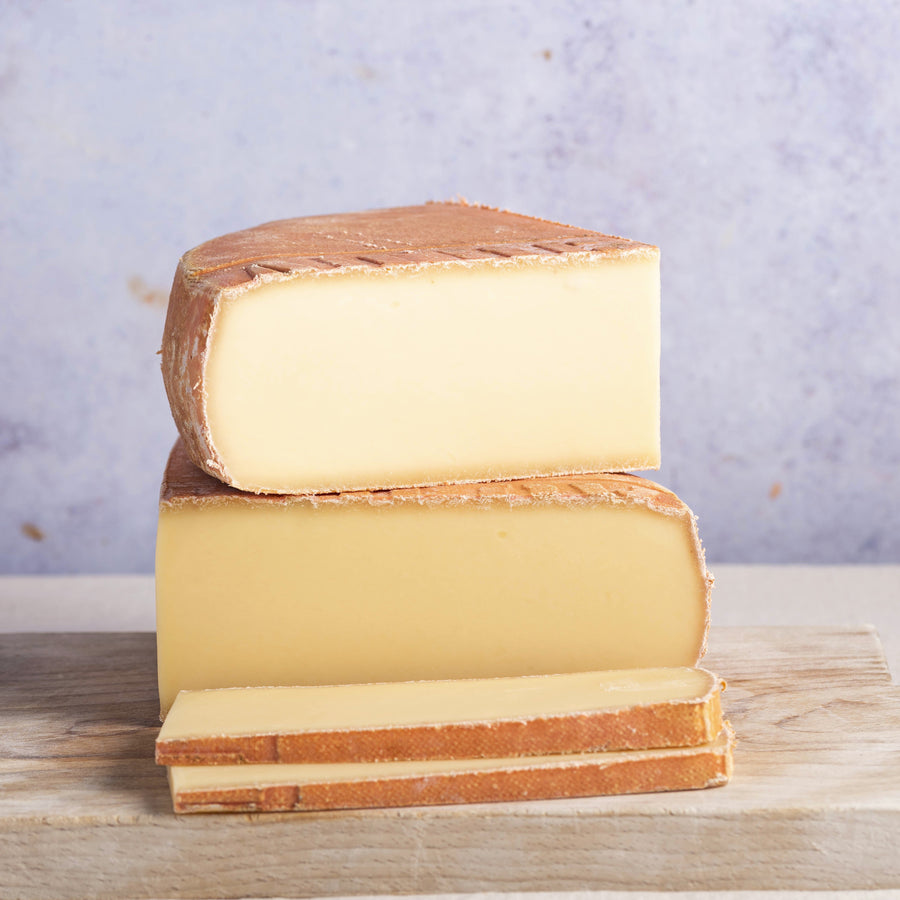 Stack of cheese wedges on a wooden board with a light purple background