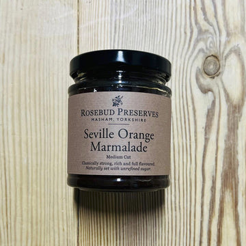 A jar of Seville Orange Marmalade on a wooden table.