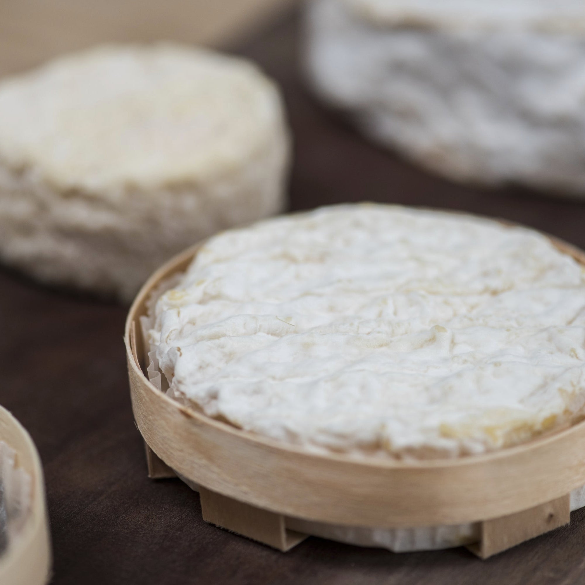 Round white cheeses on a wooden surface with a bamboo tray.