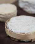 Round white cheeses on a wooden surface with a bamboo tray.