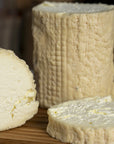 Small and large cut pieces of St. Tola goat's cheese on a wooden board.
