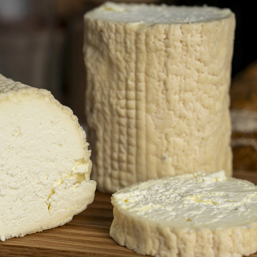 Small and large cut pieces of St. Tola goat's cheese on a wooden board.