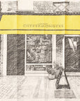 A tea towel depicting the front of a shop with a yellow awning.