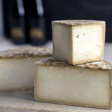 Cut pieces of Tinto hard goat's milk cheese on a wooden board.
