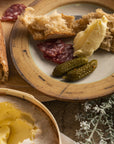 Platter with bread, butter, and cured meats on a wooden surface